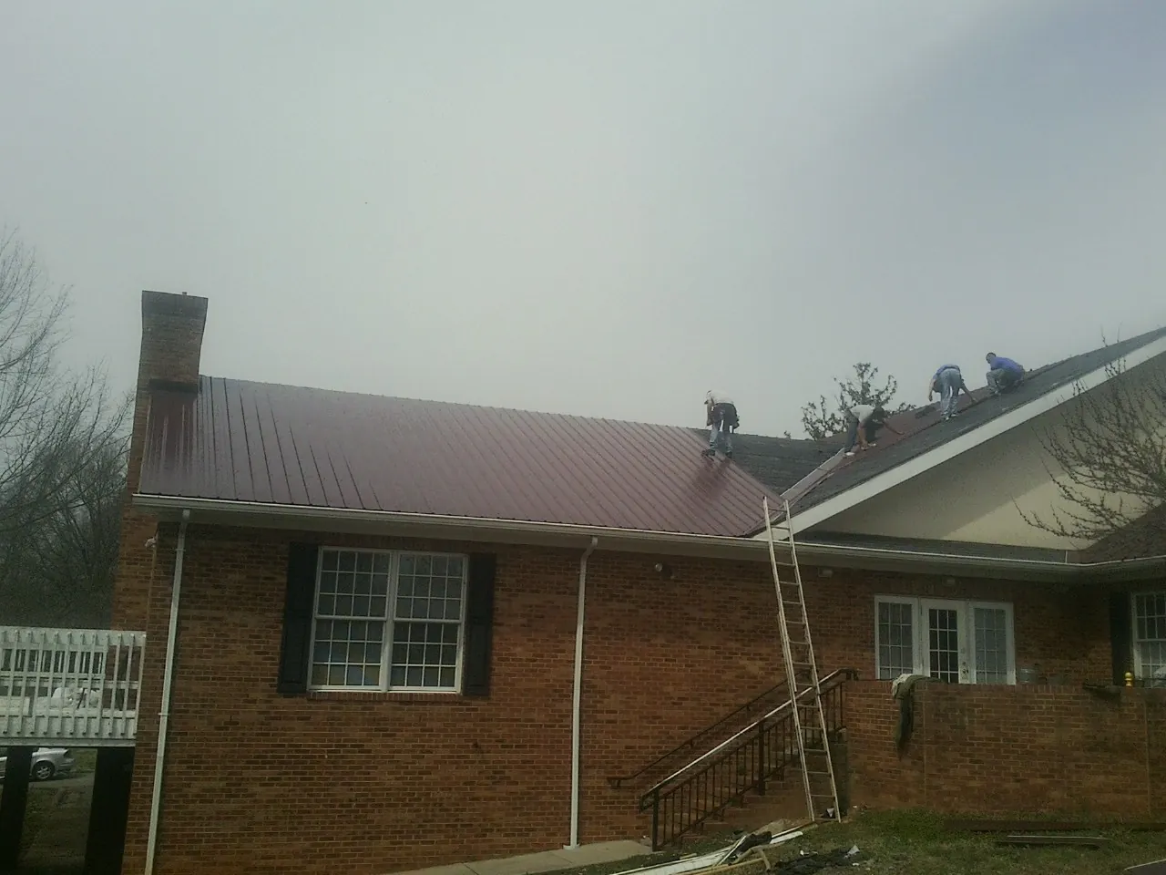Crew setting red metal roofing panels on a brick home in Elmwood Park