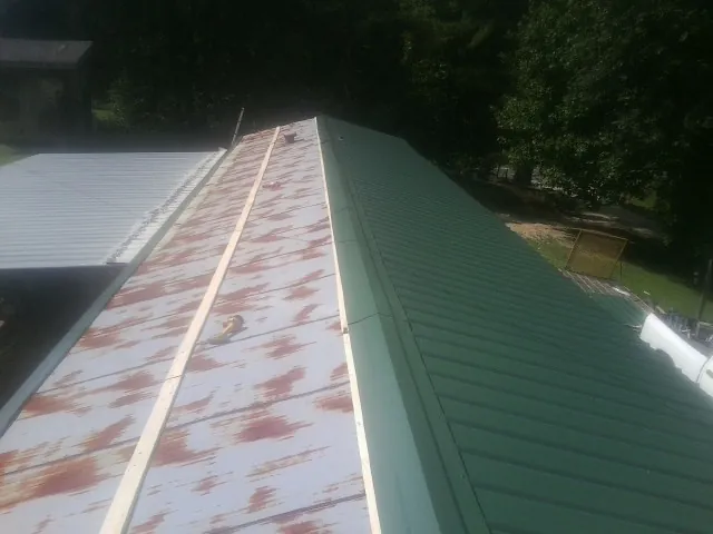 Old rusted panels beside newly installed green metal roofing — Wind Damage Roof Repair by Roofing Brothers in Elmwood Park