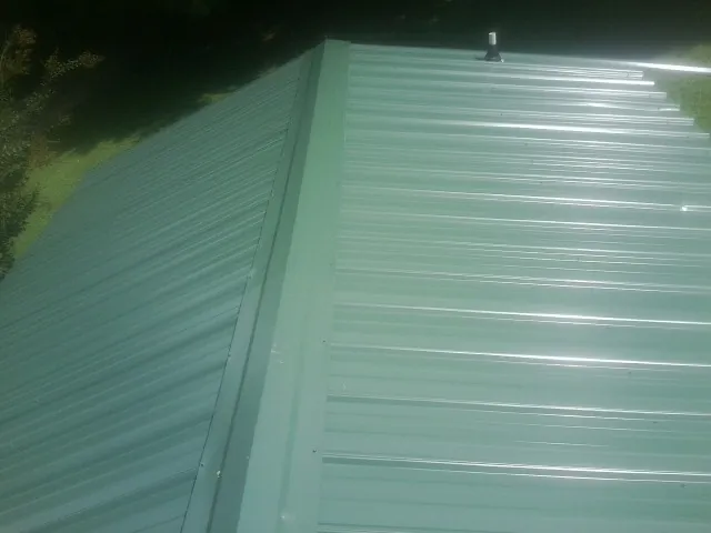 New green metal panels meeting at the ridge of a roof — Flat Roof Repair work by our crew in Elmwood Park
