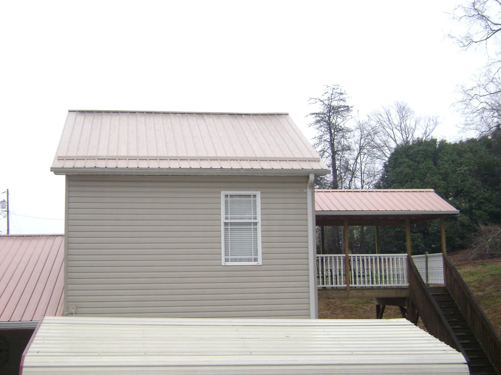 Tan metal roofs on a two story addition and attached porch, from a Roof Replacement job in Elmwood Park