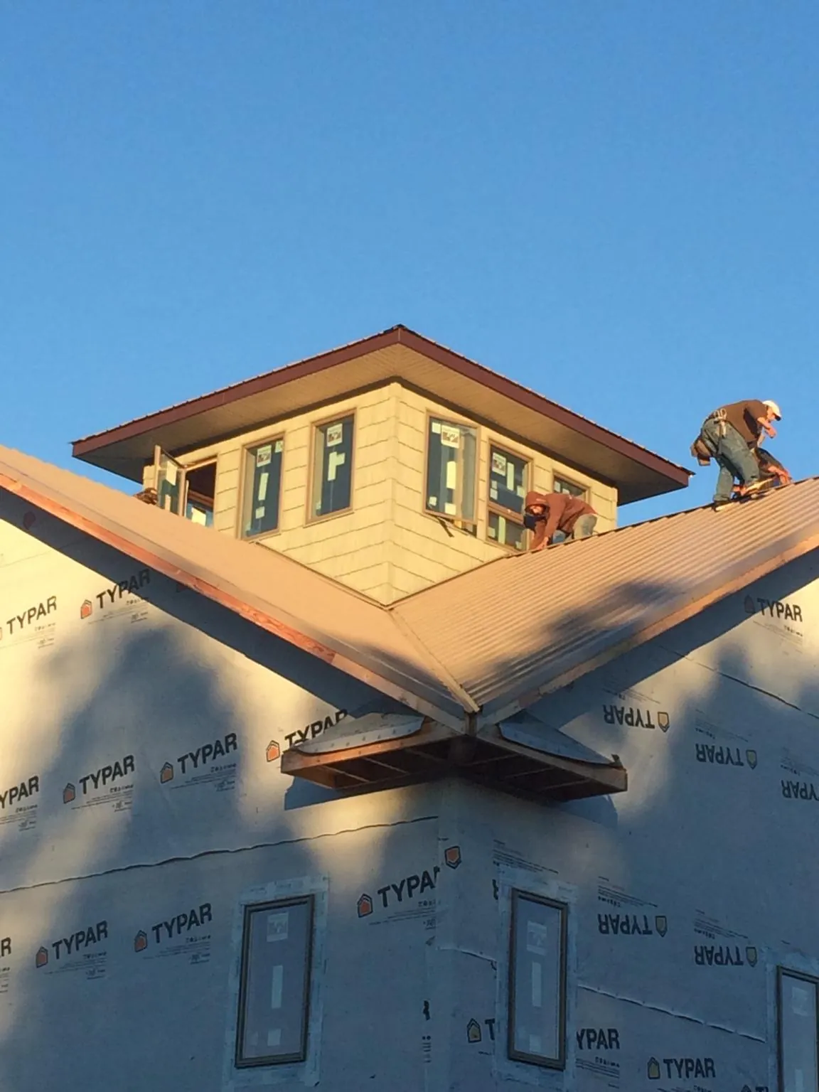 Roofers working around a rooftop cupola on a new metal roof at sunset — Roof Waterproofing in Elmwood Park by Roofing Brothers